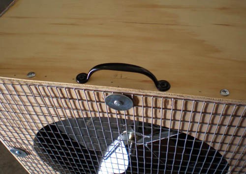 A handle is attached on the top side of a diffuser box above the fan