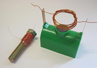 Magnet wire wrapped around a screw next to a plastic electromagnetic motor