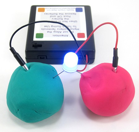 A lit LED bridges two Play-Doh balls connected to a battery pack