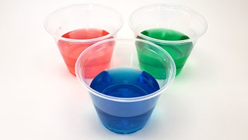 Three side-by-side plastic cups filled with red, green and blue water