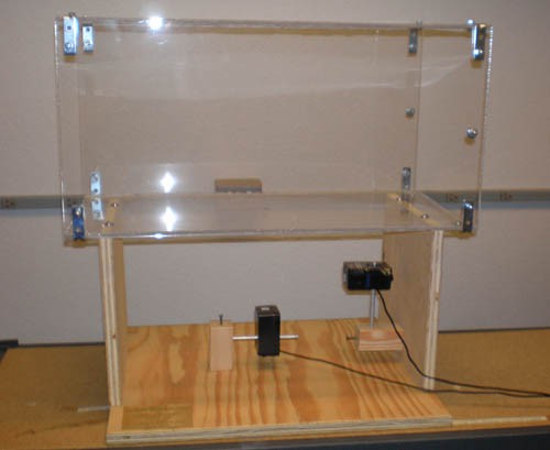 A retangular Plexiglas case sits on a wooden frame