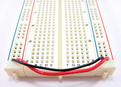 Photo of jumper wires connecting opposite side buses on a breadboard